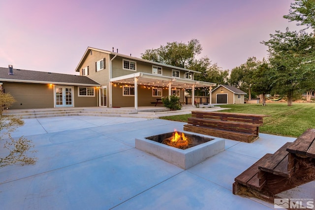 back house at dusk with an outdoor fire pit, a pergola, a yard, and a patio