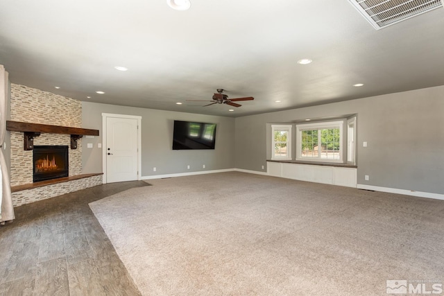 unfurnished living room featuring carpet flooring, ceiling fan, and a large fireplace