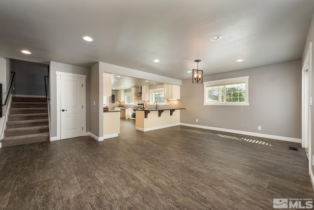 unfurnished living room featuring dark hardwood / wood-style floors, a notable chandelier, and sink