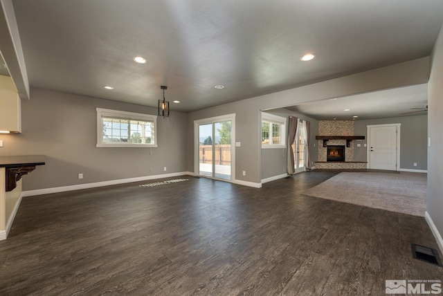 unfurnished living room with ceiling fan, a fireplace, and dark hardwood / wood-style floors