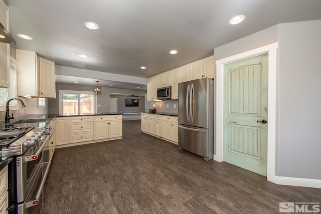 kitchen with pendant lighting, stainless steel appliances, kitchen peninsula, sink, and dark hardwood / wood-style floors