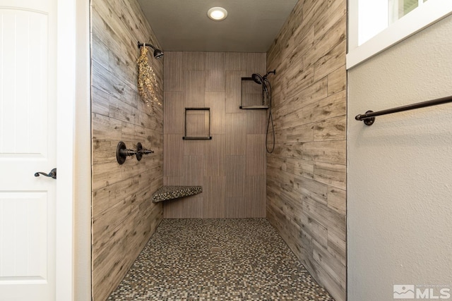 bathroom featuring wood walls and a tile shower