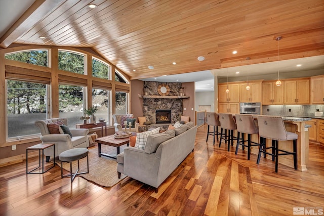 living room featuring wood ceiling, light hardwood / wood-style flooring, high vaulted ceiling, and a fireplace