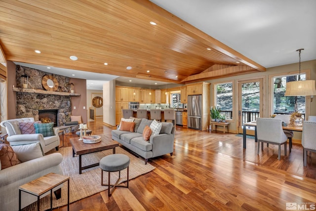 living room with a fireplace, lofted ceiling with beams, and light hardwood / wood-style flooring