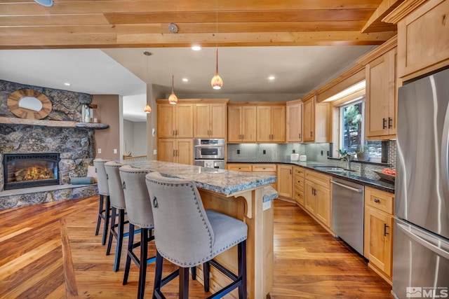 kitchen featuring stainless steel appliances, a kitchen breakfast bar, light brown cabinetry, and light hardwood / wood-style floors