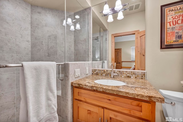 bathroom featuring vanity, toilet, walk in shower, and tasteful backsplash