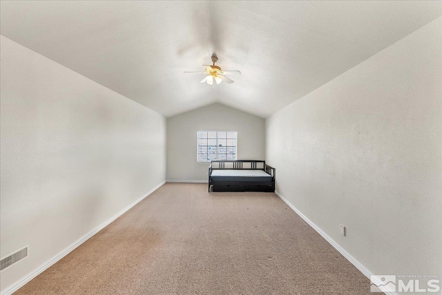 unfurnished bedroom with light colored carpet, lofted ceiling, ceiling fan, and a textured ceiling