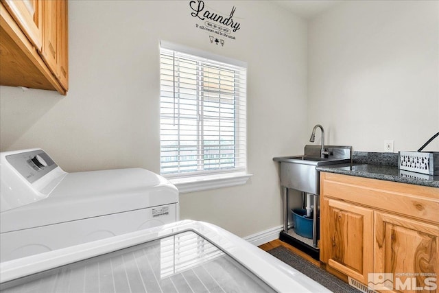 clothes washing area featuring washer and dryer, cabinets, and sink