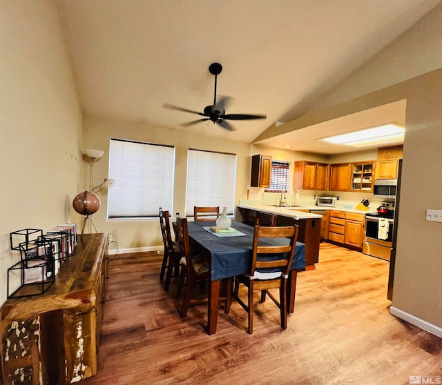 dining space featuring lofted ceiling, ceiling fan, sink, and light hardwood / wood-style floors