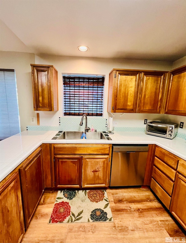 kitchen with stainless steel dishwasher, sink, and light hardwood / wood-style flooring