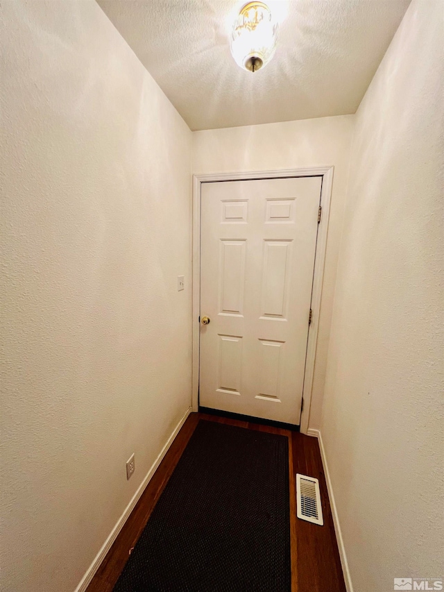 doorway with dark hardwood / wood-style floors and a textured ceiling