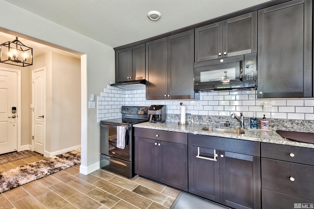 kitchen with backsplash, light stone countertops, a notable chandelier, sink, and black appliances
