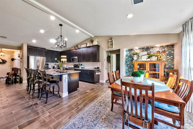 dining space featuring dark wood-type flooring, an inviting chandelier, and lofted ceiling with beams