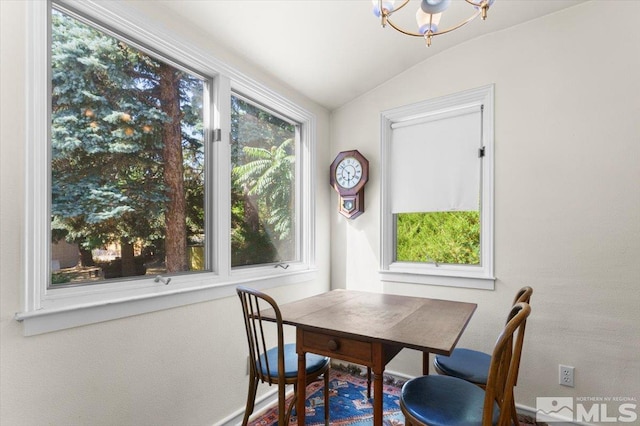 dining room with lofted ceiling, a healthy amount of sunlight, and a notable chandelier