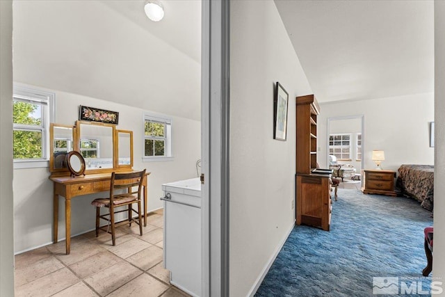 hallway featuring light colored carpet, a wealth of natural light, and vaulted ceiling