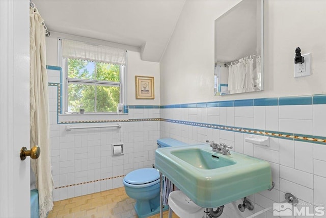 bathroom featuring walk in shower, toilet, sink, tile walls, and decorative backsplash