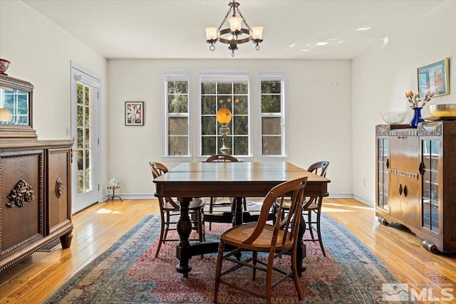 dining room with a wealth of natural light, hardwood / wood-style floors, and an inviting chandelier