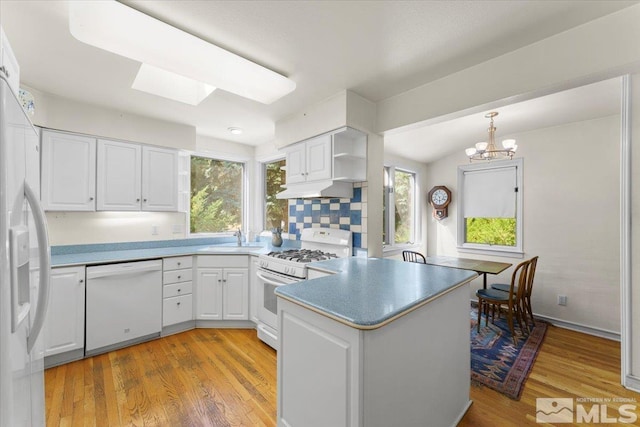 kitchen featuring white appliances, a notable chandelier, light hardwood / wood-style floors, kitchen peninsula, and white cabinets