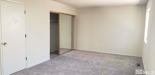 unfurnished bedroom featuring carpet, a closet, baseboards, and a textured ceiling