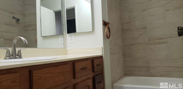 bathroom with tiled shower / bath and vanity