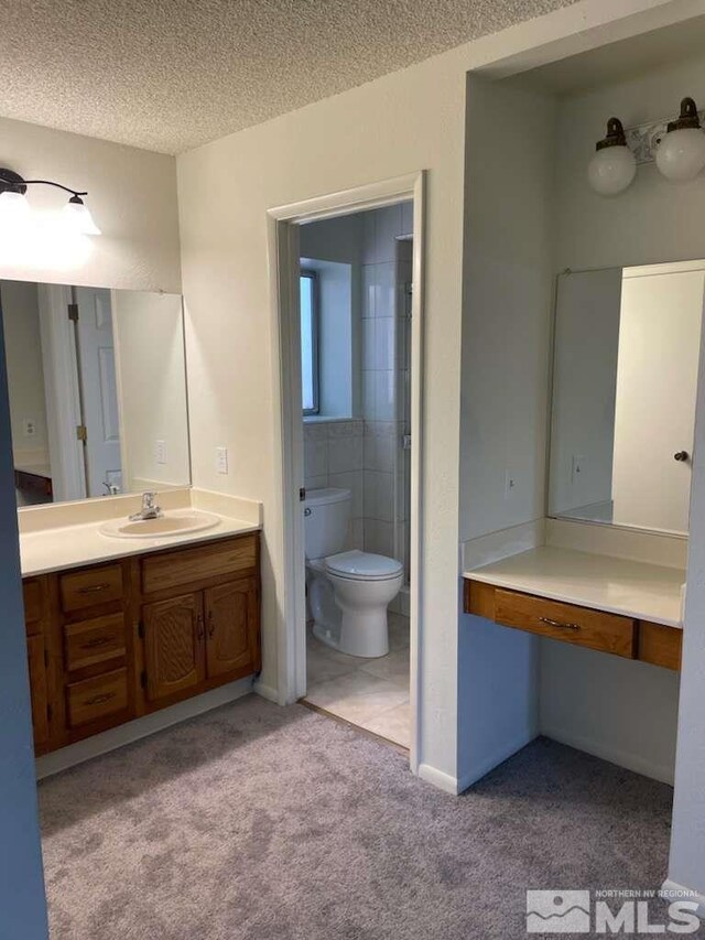 bathroom with vanity, toilet, tile patterned floors, and a textured ceiling