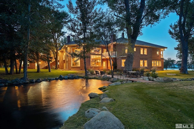 back house at dusk with a yard and a patio area