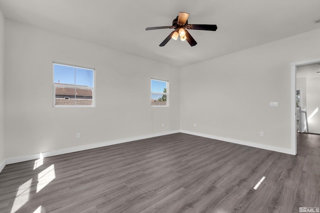 empty room with ceiling fan, a healthy amount of sunlight, and dark hardwood / wood-style floors