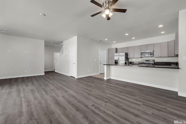 unfurnished living room with a ceiling fan, recessed lighting, dark wood finished floors, and baseboards