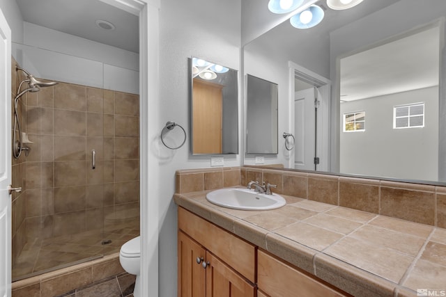 bathroom with tiled shower, vanity, and toilet