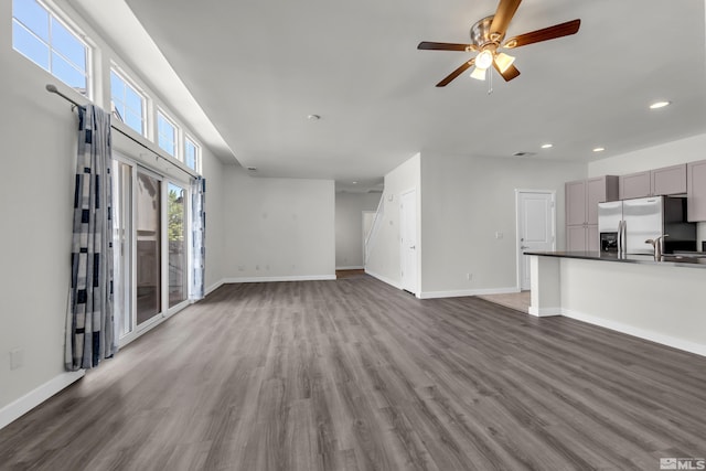 unfurnished living room with dark hardwood / wood-style flooring and ceiling fan