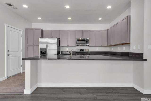 kitchen featuring stainless steel appliances, gray cabinets, dark hardwood / wood-style floors, and kitchen peninsula