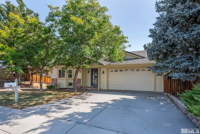 view of front of property with a garage, driveway, brick siding, and fence