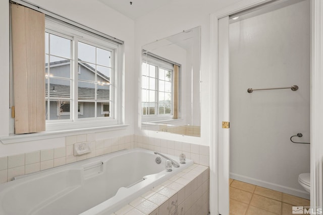 bathroom with a garden tub, toilet, baseboards, and tile patterned floors