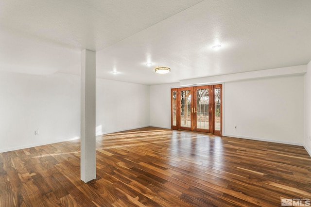 empty room with baseboards, wood finished floors, and french doors