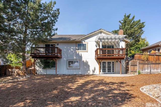 rear view of property featuring french doors, fence, a wooden deck, and a pergola