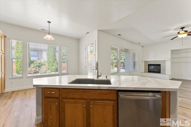 kitchen featuring dishwasher, a kitchen island with sink, sink, ceiling fan, and light wood-type flooring