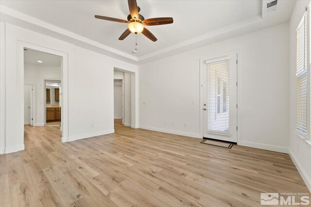 interior space featuring a tray ceiling, ceiling fan, a wealth of natural light, and light hardwood / wood-style flooring