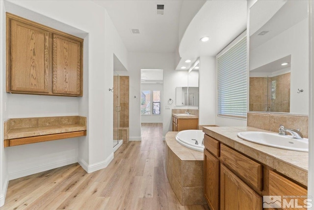 bathroom featuring vanity, wood-type flooring, and plus walk in shower