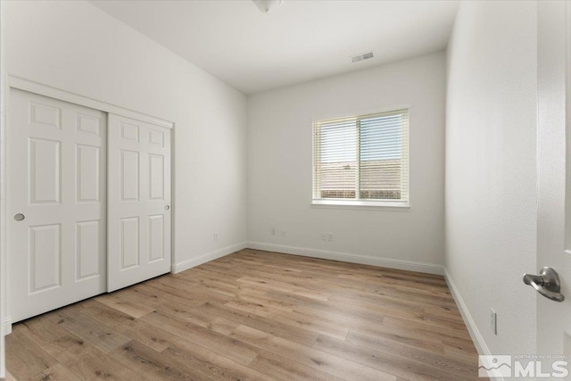 unfurnished bedroom with light wood-type flooring and a closet