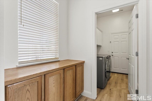 clothes washing area with light wood-type flooring, cabinets, and washer and clothes dryer