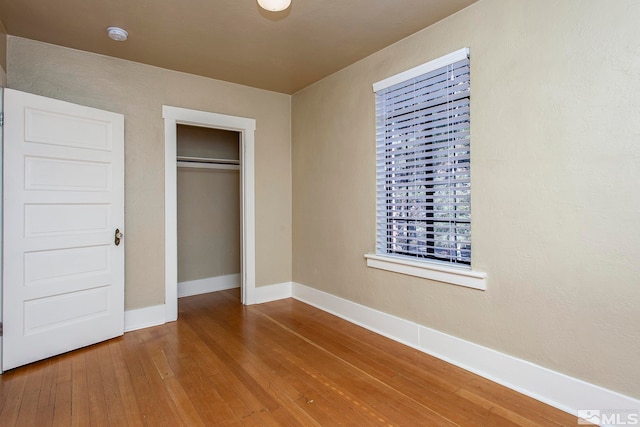 unfurnished bedroom with hardwood / wood-style flooring and a closet