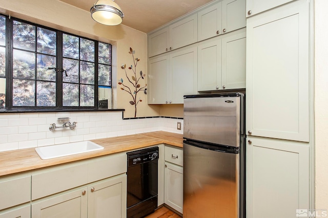 kitchen with stainless steel refrigerator, dishwasher, wooden counters, sink, and decorative backsplash