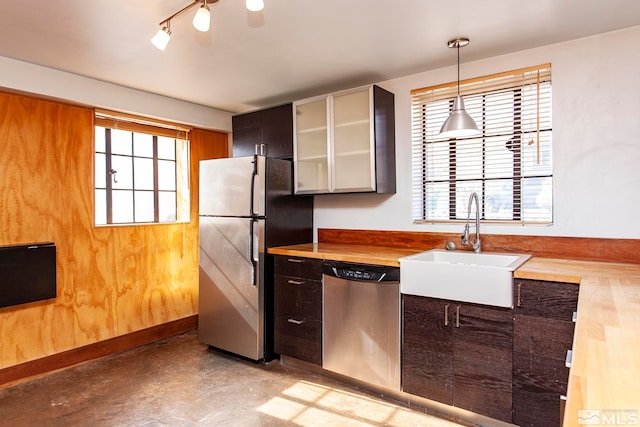 kitchen with stainless steel appliances, sink, decorative light fixtures, and butcher block countertops