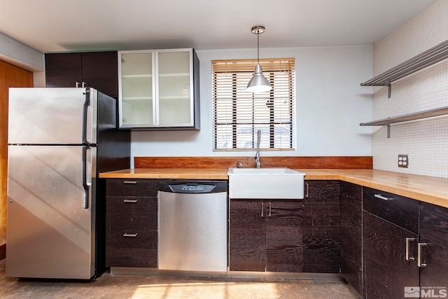 kitchen featuring hanging light fixtures, wood counters, appliances with stainless steel finishes, sink, and dark brown cabinetry