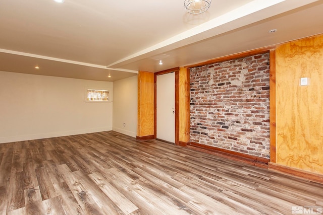 empty room featuring brick wall and wood-type flooring