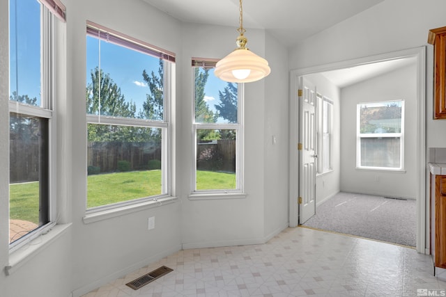 unfurnished dining area featuring baseboards, visible vents, and vaulted ceiling