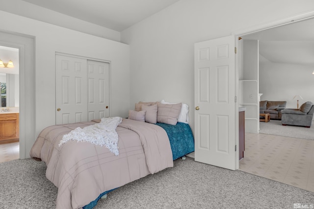 carpeted bedroom with ensuite bath and a closet