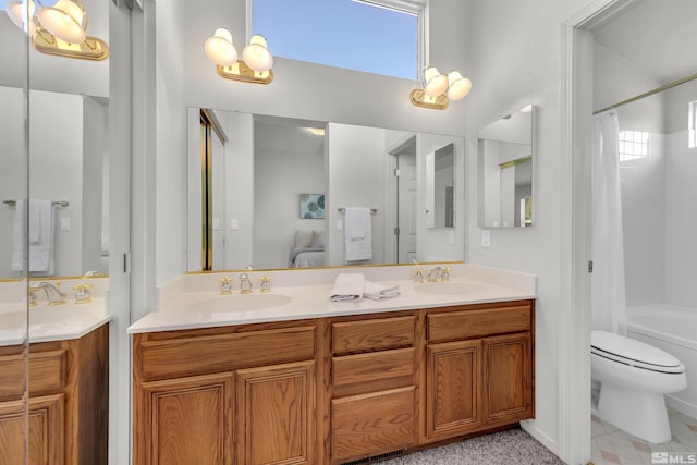 bathroom with double vanity, toilet, and a sink