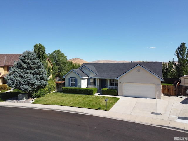 single story home with concrete driveway, an attached garage, fence, a mountain view, and a front lawn