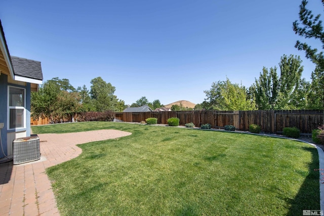 view of yard featuring a fenced backyard, a patio, and central AC